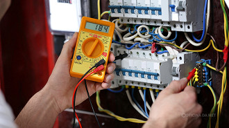 Um eletricista usa um multímetro para medir a tensão de uma rede elétrica Um eletricista usa um multímetro para medir a tensão de uma rede elétrica