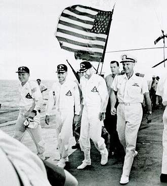 Os astronautas da Apollo 8 e o oficial comandante do navio de recuperação USS Yorktown caminham pelo tapete vermelho da plataforma de vôo após a recuperação do splashdown no Oceano Pacífico