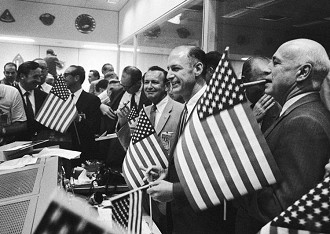 Chris Kraft, no centro, segurando um charuto no alto, comemora o retorno da tripulação da Apollo 11 à Terra em 24 de julho de 1969. À sua direita estão George Low e Robert Gilruth