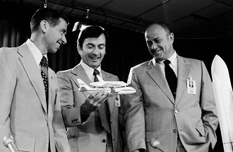 O gerente do programa Space Shuttle Bob Thompson, à direita, é mostrado em 1974 com Aaron Cohen e o astronauta John Young. Young está segurando um modelo do ônibus em sua aeronave