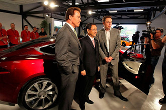 O então governador da Califórnia, Arnold Schwarzenegger, o CEO da Toyota, Akio Toyoda, e Elon Musk, posam na frente de um Tesla Model S na inauguração da nova fábrica da Tesla