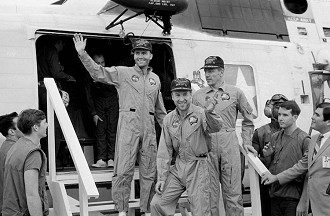 Fred Haise, à esquerda, Jim Lovell, no centro, e Jack Swigert pisa no convés do porta-aviões Iwo Jima