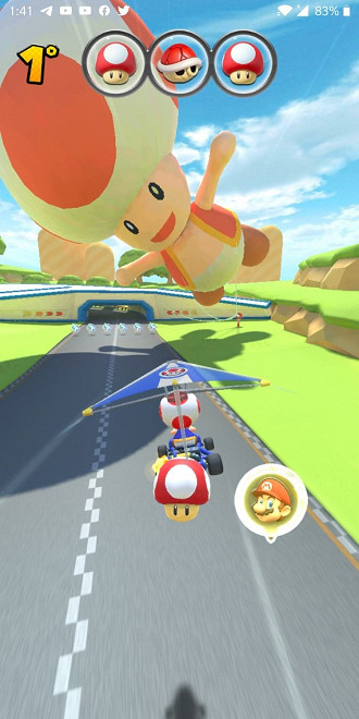 Cena do jogo Mario Kart Tour com Toad sobrevoando a pista Cena do jogo Mario Kart Tour com Toad sobrevoando a pista