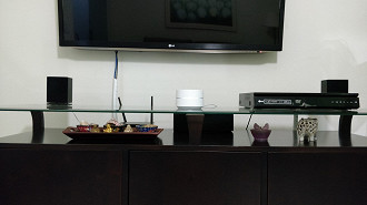 Roteador Google Wi-fi no centro do móvel da sala de TV. Fonte: Vitor Valeri